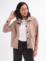 Campera de pana color beige, con cuello camisero, cierre frontal de botones oscuros, mangas largas con puños abotonados y dos bolsillos frontales con solapa.