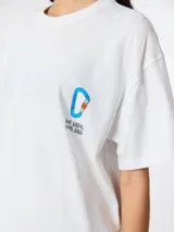 Camiseta blanca de algodón orgánico con corte oversize, estampado de un mosquetón azul y texto en el lateral superior izquierdo y estampado en la espalda.