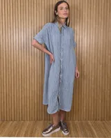 Vestido midi estilo túnica camisera con estampado de rayas verticales en tonos celeste y blanco, cuello camisero, cierre frontal con botones ocultos y mangas cortas holgadas.