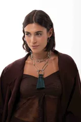 Collar de cadena con eslabones rectangulares metálicos en tono plateado, con diseño versátil que permite usarlo largo o doble. Incluye un dije central en forma de herradura con un aplique de borla de hilos en color verde oscuro.