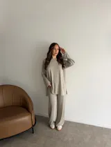 Conjunto de dos piezas de lanilla en color gris melange, compuesto por un buzo oversize de manga larga con aberturas laterales y un pantalón largo de corte recto y holgado.