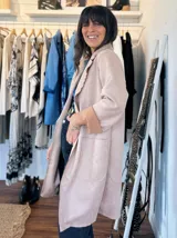 Chaqueta color rosa pálido de gamuza sintética, corte recto, con cuello tipo solapa y mangas 3/4 con puños en color beige.