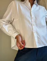 Camisa blanca de manga larga con puños abullonados y bordado en el puño.
