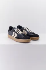 Zapatillas de cuero negro con detalles en gamuza negra en la puntera y el talón. Presenta el logo de la marca en color beige en el lateral y suela color caramelo.