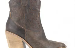 Bota corta estilo texana color negro, confeccionada en cuero, con taco foliado de suela natural de 6 cm.