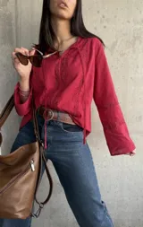 Blusa roja de manga larga con escote en V con cordones y detalles de encaje.