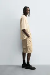 Bermuda de corte relajado en denim de algodón color beige, estilo cargo, con cinco bolsillos y bolsillos plastrón con solapa en las perneras.