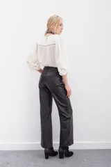 Pantalón de cuero ovino con corte oxford y tiro medio. Presenta diseño de cinco bolsillos, cierre frontal con botón metálico y costuras horizontales a la altura de la rodilla.