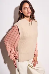 Chaleco de punto color beige con cuello alto y sisas amplias.