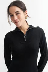 Vestido corto de tejido de punto acanalado en color negro, con cuello polo y cierre frontal parcial. Presenta mangas largas y un ajuste entallado al cuerpo.