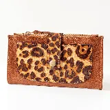 Billetera de cuero color marrón con bolsillo frontal con solapa y cierre con broche a presión, con estampado animal print. Tiene dos bolsillos con cierre en los extremos y dos bolsillos para tarjetas en el interior.