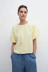 Blusa amarilla con estampado floral, mangas cortas abullonadas y cuello redondo.