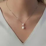 Conjunto de collar y aros en plata 925 con perlas de río y circonias. El collar tiene una cadena de 42cm y dos perlas colgantes de 6,5mm y 8,5mm.