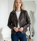 Campera estilo biker de ecocuero en color marrón oscuro, con cierre frontal cruzado, solapas clásicas y bolsillos laterales con cierre.