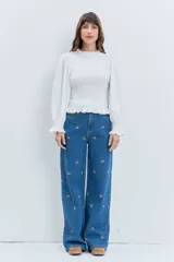 Jean de corte wide leg en color azul medio, con diseño de pequeños bordados dispersos en toda la prenda. Presenta cierre frontal con botón y bolsillos laterales.