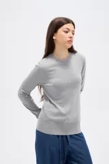 Sweater de lyocell al cuerpo, con cuello redondo a la base y mangas largas con detalle de botones en los puños.