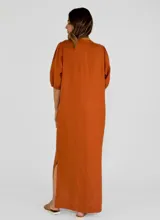 Vestido midi color beige, de corte recto y holgado, con mangas cortas abullonadas, escote en V con solapa abotonada en contraste marrón y tajo lateral en el bajo.