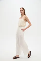 Pantalón de lino blanco, de corte ancho y tiro alto con cintura elástica fruncida y cordón ajustable.