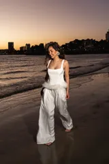 Pantalón palazzo de satén color blanco, fluido y con cintura elástica. Presenta detalle de plumas en la cintura.