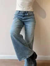 Pantalón de jean con corte wide leg y tiro medio-alto. Presenta un lavado gris azulado desgastado con acabado vintage y ruedo desflecado.