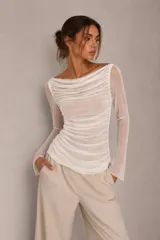 Blusa de tul transparente color gris, con diseño drapeado en todo el cuerpo, escote bote y mangas largas.