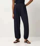 Pantalón largo femenino texturizado color azul marino, modelo aladim, con volumen amplio en las piernas y estrechamiento en el ruedo. Posee cintura elástica incorporada y pliegues delanteros.