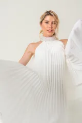 Vestido largo blanco de gasa plisada, sin mangas y con cuello halter bordado con perlas.