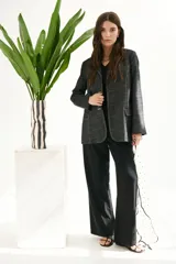 Pantalón de vestir color beige, de corte palazzo y tiro alto. Incluye cinturón de cadena plateada.