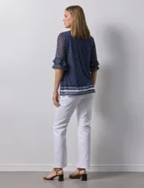 Blusa Harper de microtul estampado azul con lunares blancos, cuello redondo, escote en U con aplique de aros y mangas cortas amplias.