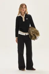 Sweater de punto con diseño de ochos en color crudo, con cuello polo y tapeta de botones en contraste verde. Presenta bordado en el pecho, puños y ruedo acanalados con detalles de rayas en verde.