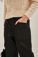 Pantalon cargo de corte recto y acabado satinado, color negro, con bolsillos laterales tipo cargo y puños elásticos en los tobillos.