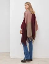 Ruana tejida con diseño colorblock en tonos de gris y beige, con flecos en el borde inferior.