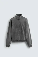 Sudadera de corte boxy fit con cuello subido y cierre frontal de cremallera. Presenta mangas largas, acabado en rib en puños y ruedo, y un diseño con efecto lavado que le otorga una apariencia única.