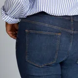 Pantalón de jean azul oscuro, de corte recto, con cinco bolsillos y ruedo doblado.