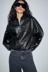 Chaqueta estilo bomber de efecto piel en color verde oliva, con cuello solapa, cierre frontal con cremallera, mangas largas y bajo elástico.