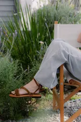 Sandalias bajas de cuero color marrón, con tiras finas para atar alrededor del tobillo.