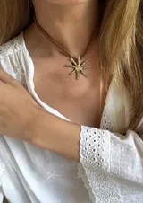 Gargantilla con doble cordón marrón y dije dorado en forma de sol.