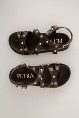 Sandalias de cuero color beige, con tiras cruzadas en el empeine decoradas con tachas y esferas doradas, base anatómica y pulsera ajustable al tobillo.