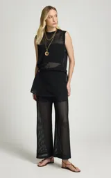 Pantalón calado negro de Le Lis Blanc, con tejido de punto transparente, corte ancho y cintura asimétrica con superposición frontal.