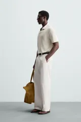 Polo negro de manga corta con cuello solapa y abertura frontal. Presenta un tejido jacquard con textura geométrica sutil.