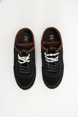 Zuecos de cuero negro con diseño tipo sneaker, cordones y suela de goma color caramelo. Presentan detalle de marca Petra en la lengüeta.