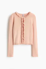 Saco de punto acanalado fino de mezcla de viscosa, color rosado, con ajuste entallado, cuello redondo y cierre frontal de botones. Presenta delicados ribetes con volados en el escote, la tapeta y el bajo.