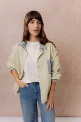 Camisa lila de calce relajado y manga larga, con cuello clásico, puños y bolsillo delantero en denim contrastante. Cierre frontal con broches metálicos.