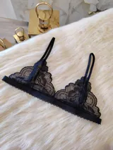 Bralette de encaje negro estilo triángulo, con breteles regulables y cierre frontal con broche de gancho.