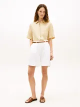 Camisa de manga corta Tommy Hilfiger de corte amplio y color beige, confeccionada en puro lino. Presenta cuello inglés, cierre frontal de botones, un bolsillo de parche en el pecho con el logo bordado y hombros ligeramente caídos.