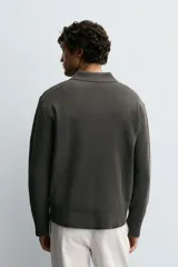 Polo de punto con textura, corte regular fit, cuello solapa con cierre frontal de tres botones, manga larga y acabados en rib.