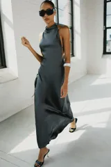 Vestido largo satinado color gris oscuro, con cuello halter, hombros descubiertos y cierre en la espalda con cremallera oculta.