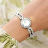 Reloj analógico Guess modelo Cassidy con caja y malla de acero inoxidable plateado. Presenta una esfera pequeña con bisel decorado con cristales y eslabones superiores también adornados con cristales.