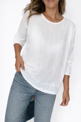 Remera blanca de manga larga con cuello redondo y detalle de tejido crochet en el dobladillo. Incluye un collar fino dorado como accesorio.