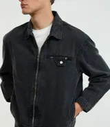 Campera de jean azul oscuro, corte boxy, con cuello inglés, cierre frontal con cremallera, manga larga y bolsillo con cierre en el pecho.